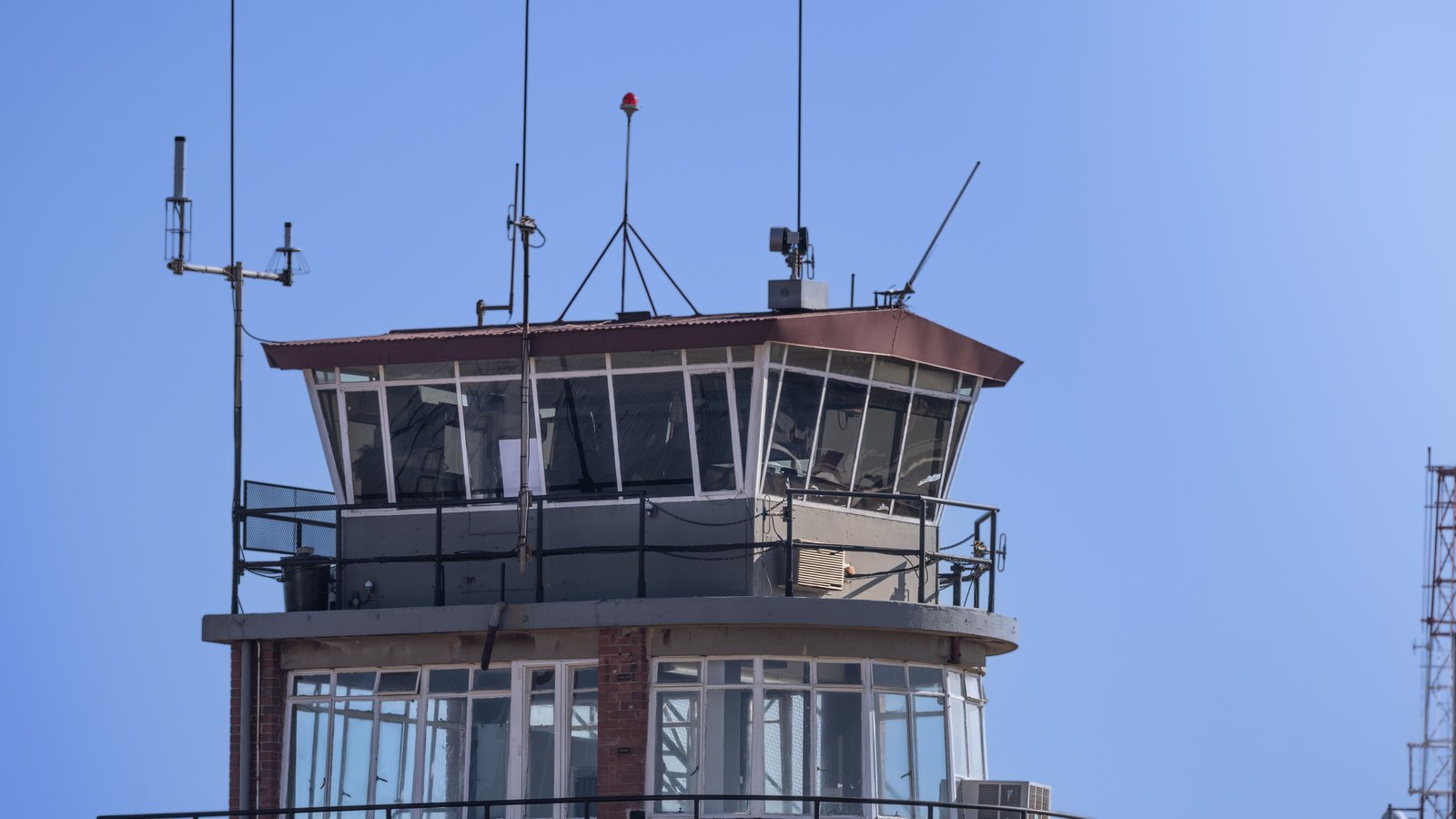 An airport control tower beneath a clear blue sky.