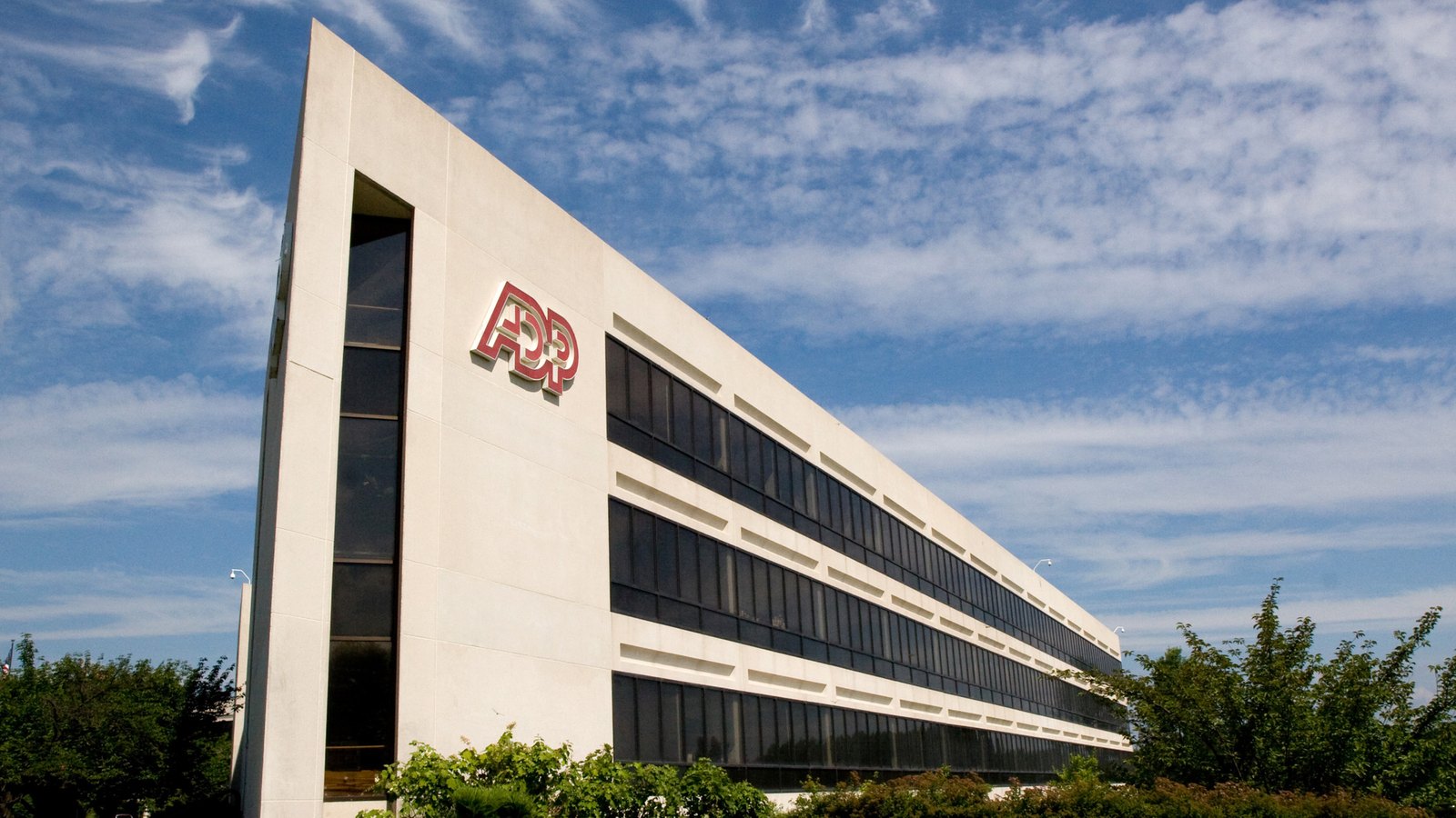 The ADP headquarters building in Roseland, New Jersey, with the company's red logo on a white facade beneath a blue sky.
