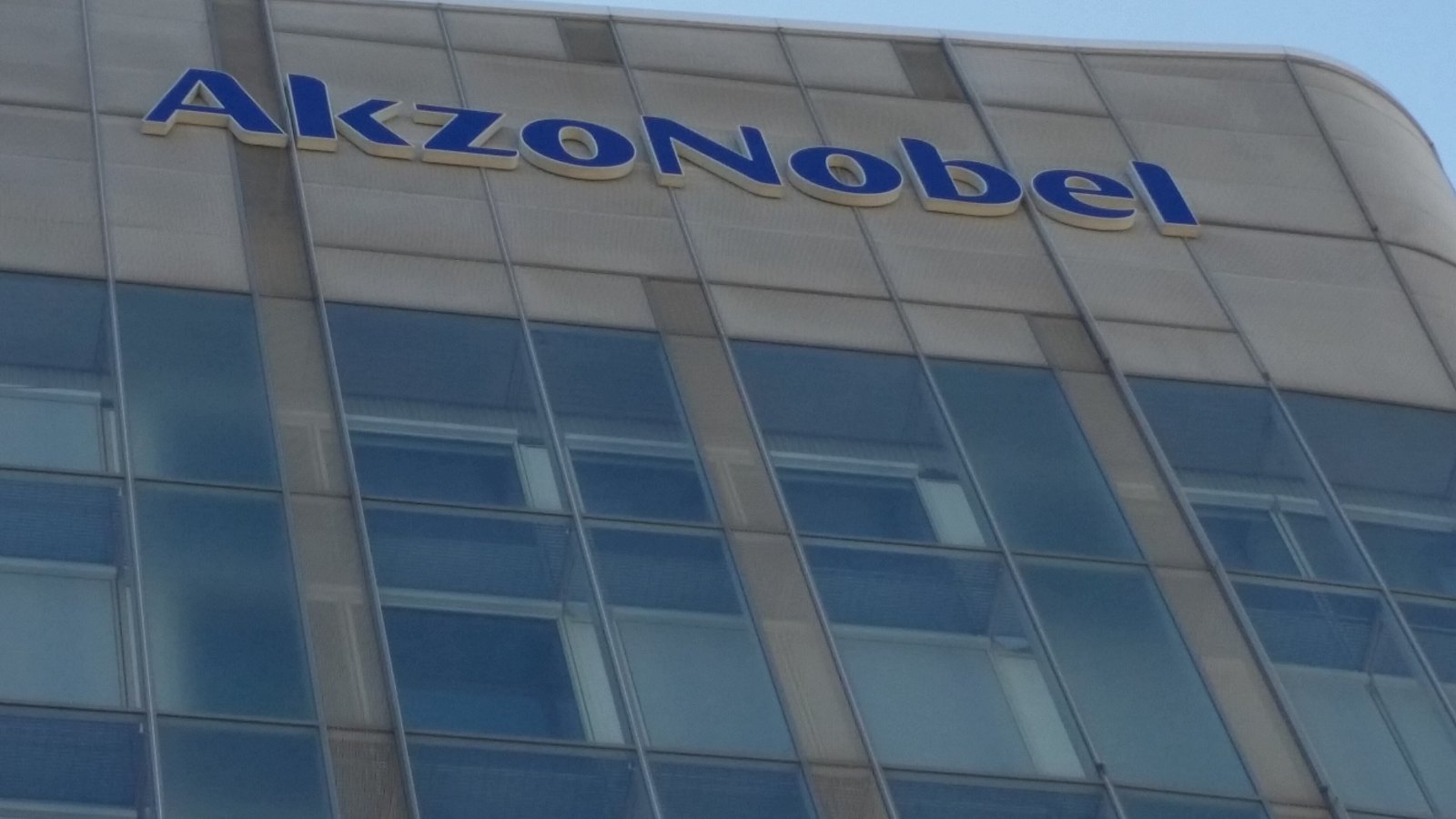 Blue AkzoNobel lettering across the top of the company's glass and pale panelled headquarters building.