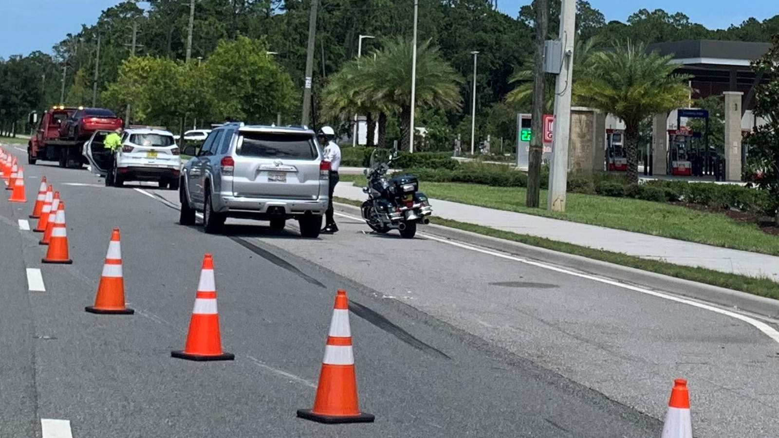 Orange cones guide traffic past stopped vehicles and a tow truck at a representative roadside incident, not this event.