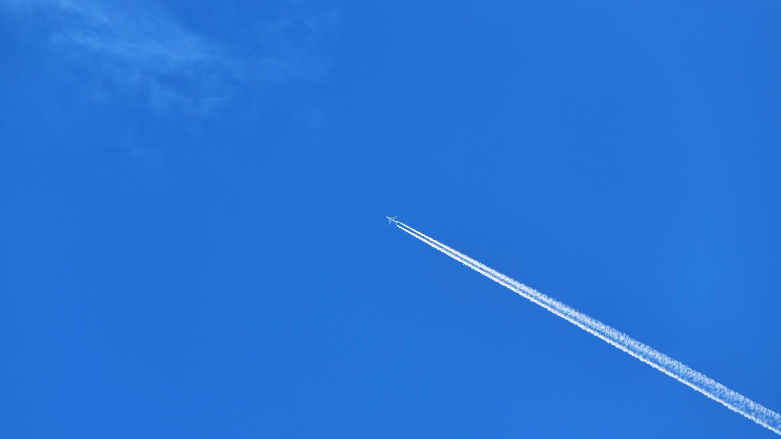 A photograph illustrating jet contrails blue sky.