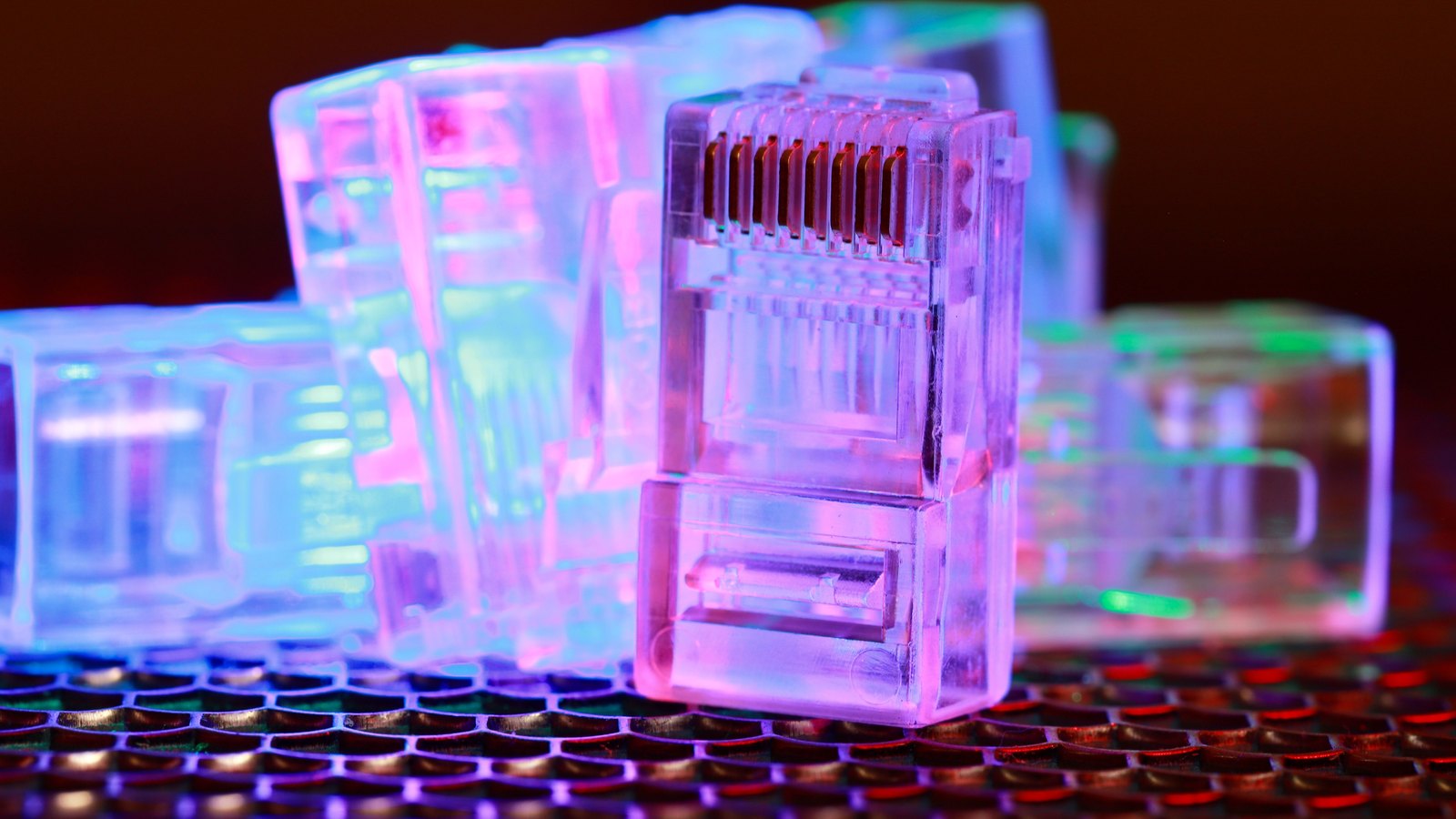 Clear Ethernet connectors lit in blue and pink on a dark surface.