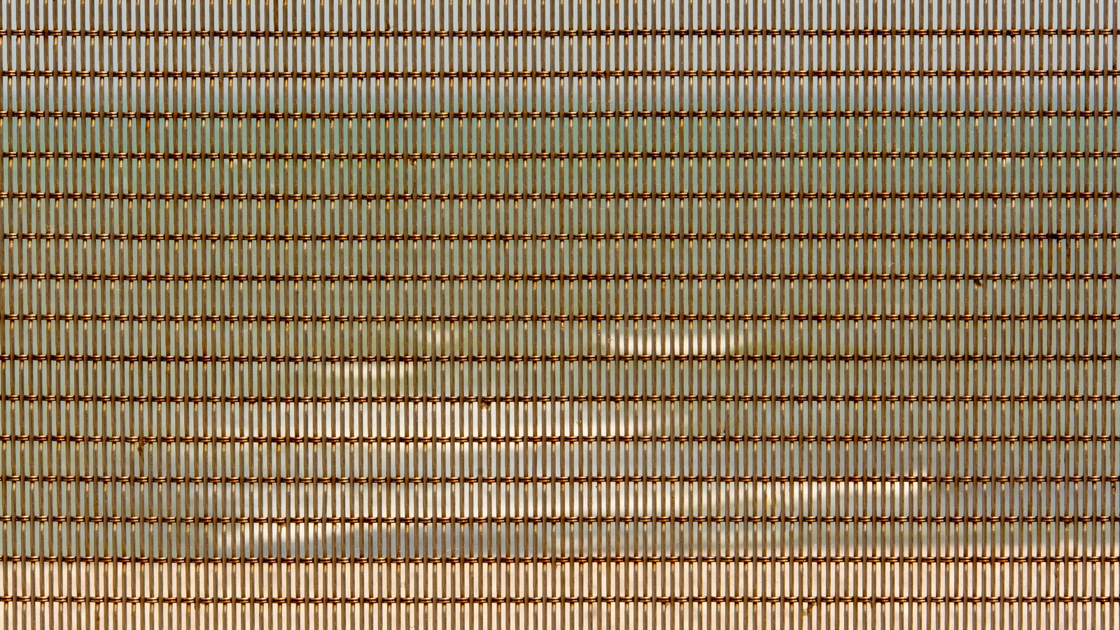 A close view of woven metal mesh, fine vertical wires crossed by regularly spaced bronze strands in a dense repeating grid.
