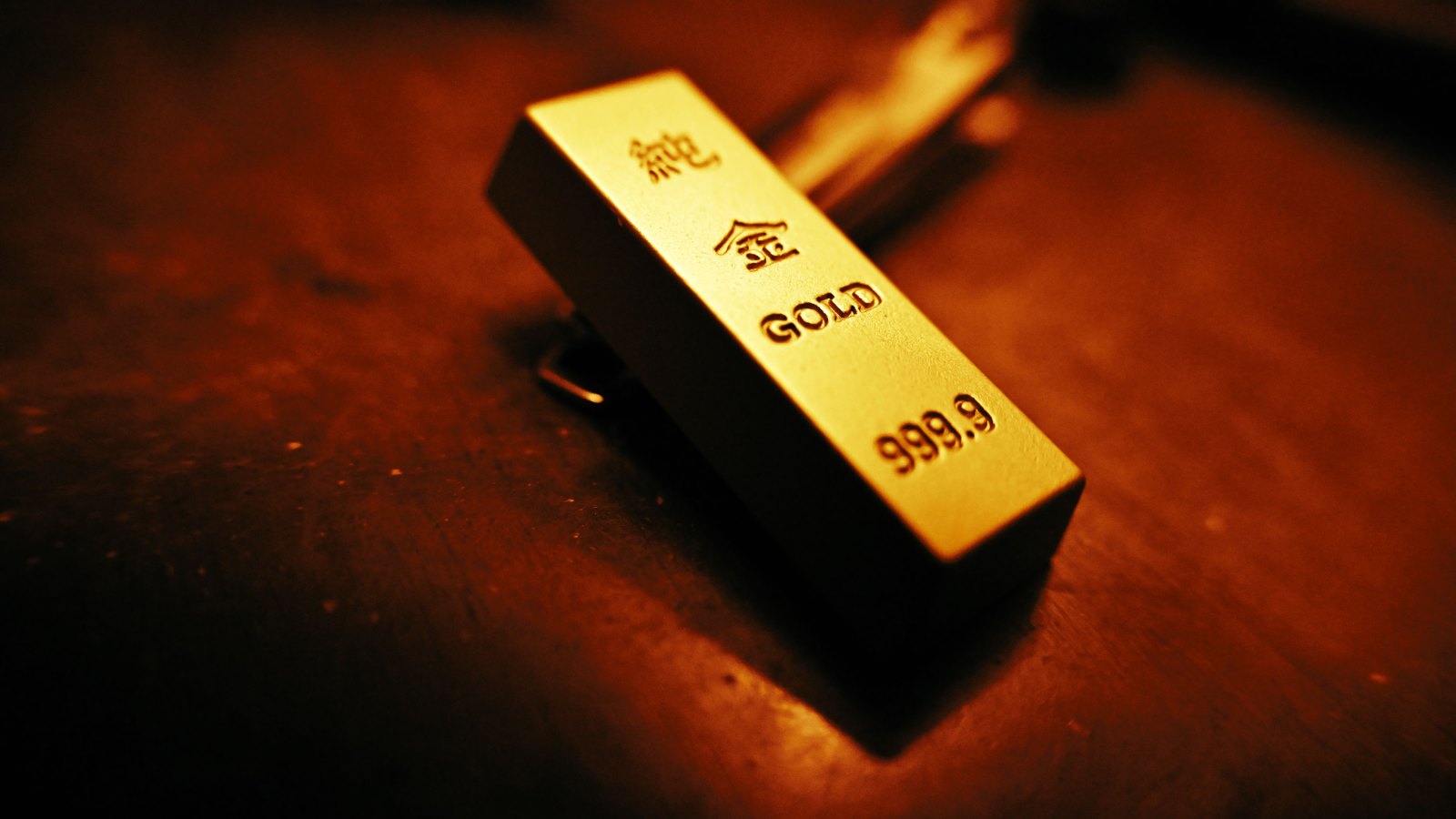 A small gold bar marked 999.9 rests on a dark reflective surface.