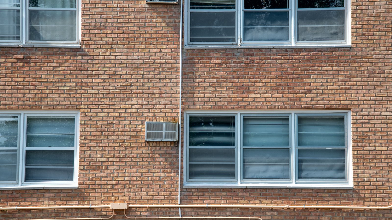 Rows of windows break up a red-brick apartment building exterior.