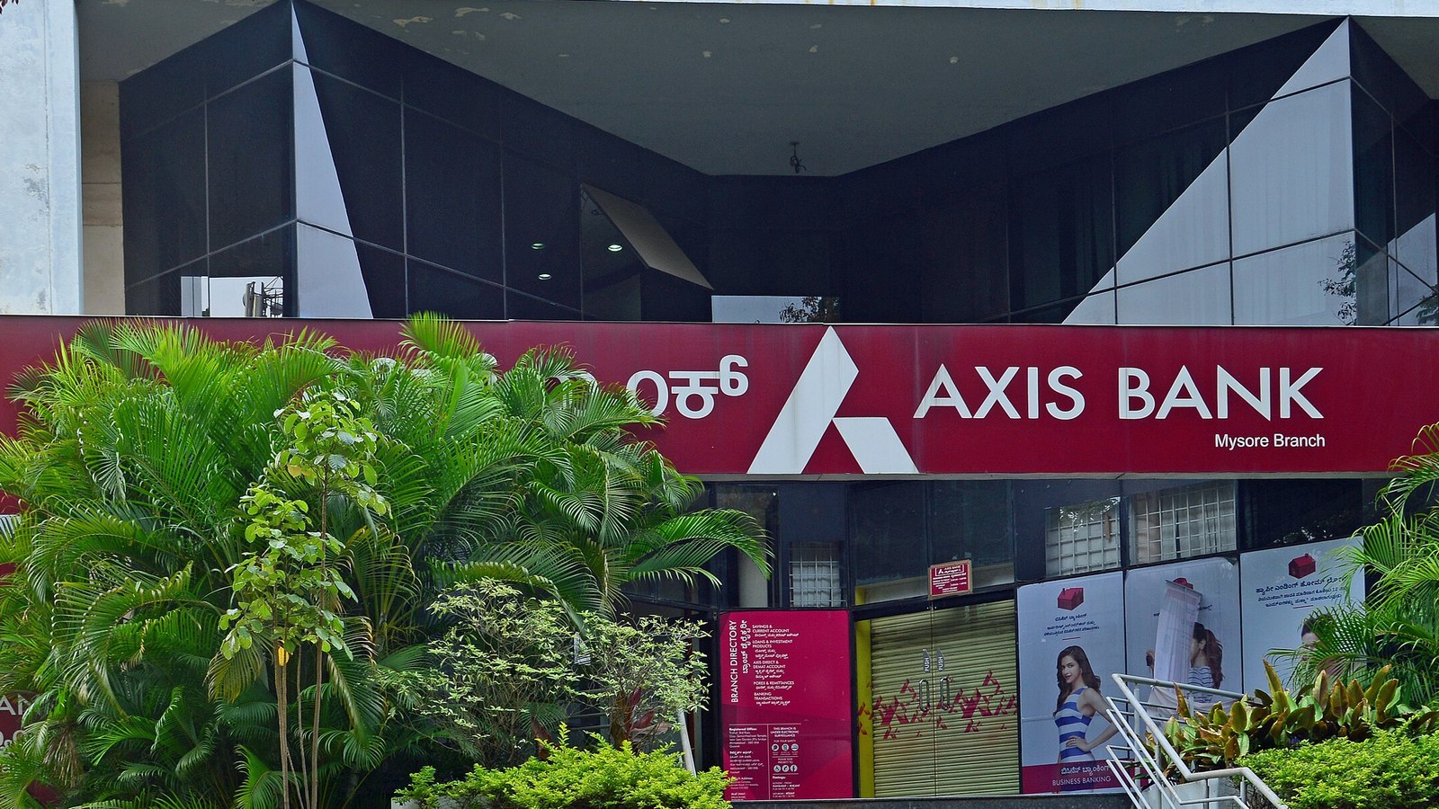 The red Axis Bank sign above the Mysore branch entrance, with palms and shrubs in front.