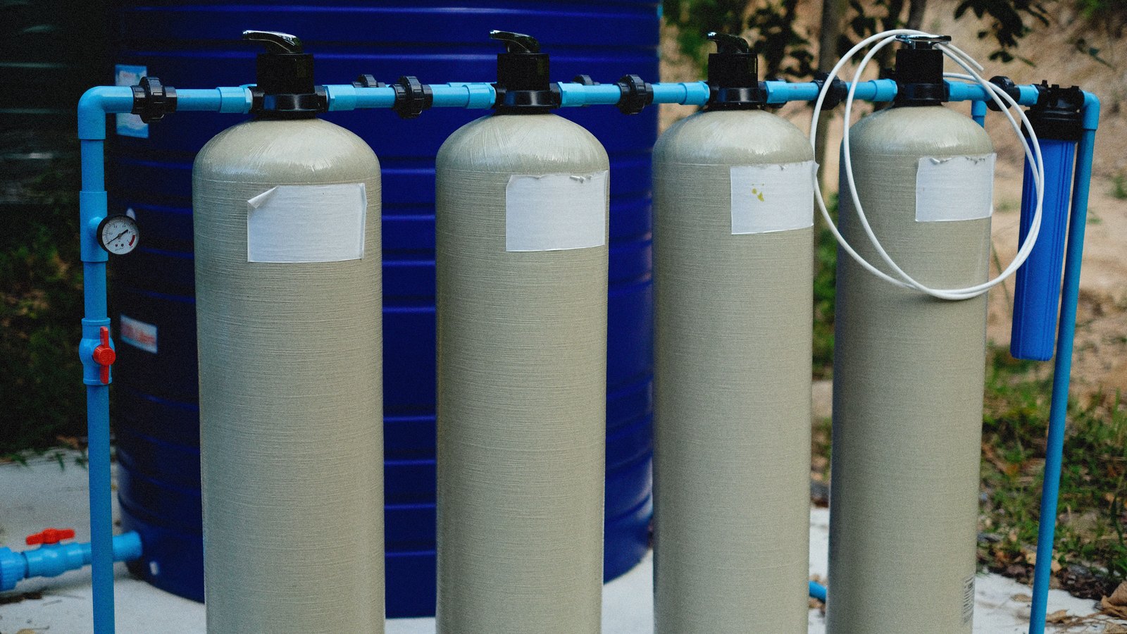 Water filtration and purification tanks with blue piping at a treatment plant.