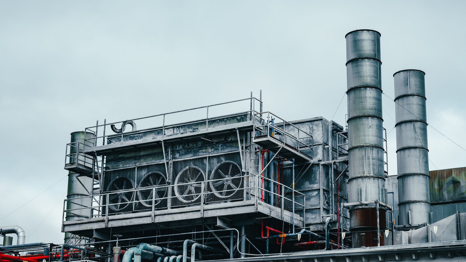 Industrial cooling equipment, metal pipes and exhaust stacks on a factory roof