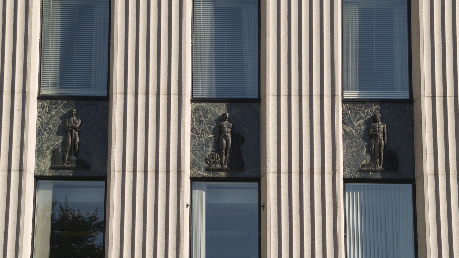 Vertical stone fins, dark marble panels and bronze figures on the Bank of Canada building in Ottawa.