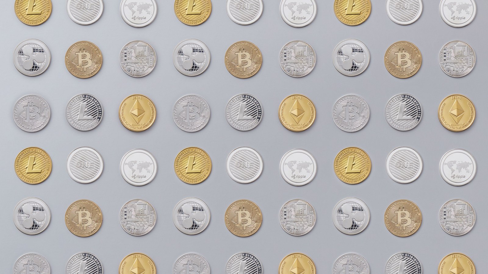 Rows of gold and silver cryptocurrency tokens, including Bitcoin, Ether, Litecoin and XRP symbols, arranged on a pale background.