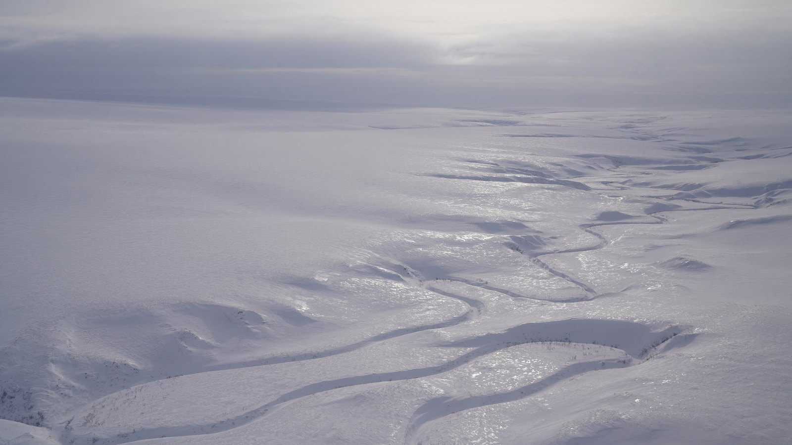 Snow-covered tundra and winding frozen waterways in the National Petroleum Reserve in Alaska.