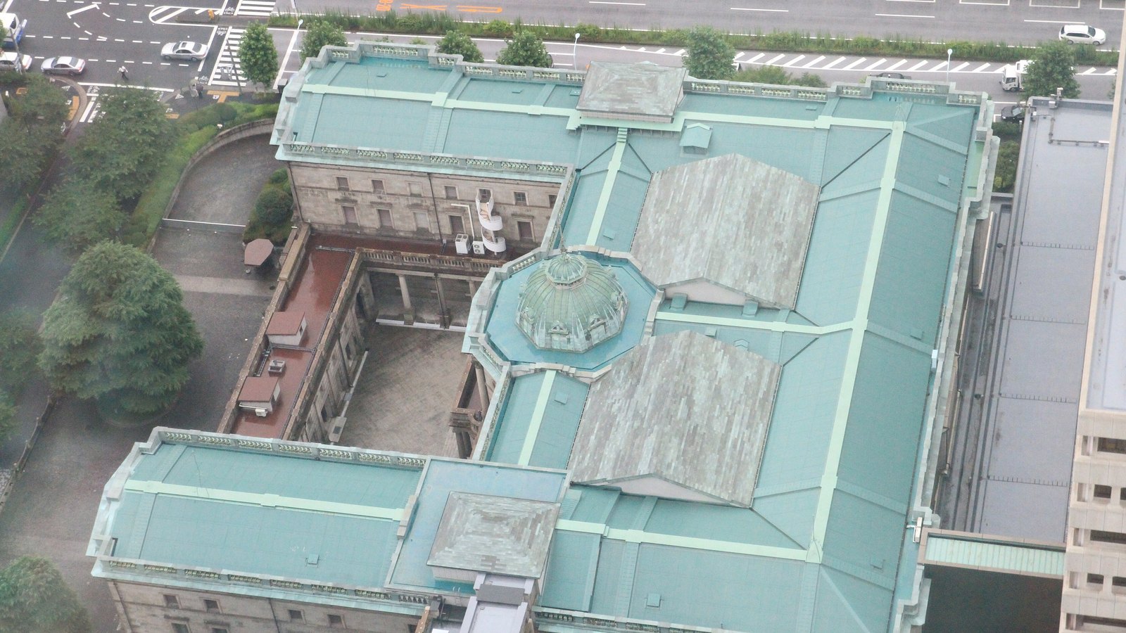 The Bank of Japan head office seen from above, with its green copper roof and central glass dome.