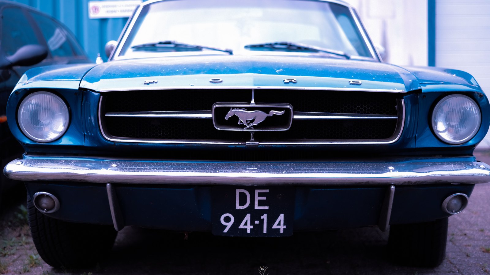 The front end of a blue first generation Ford Mustang.