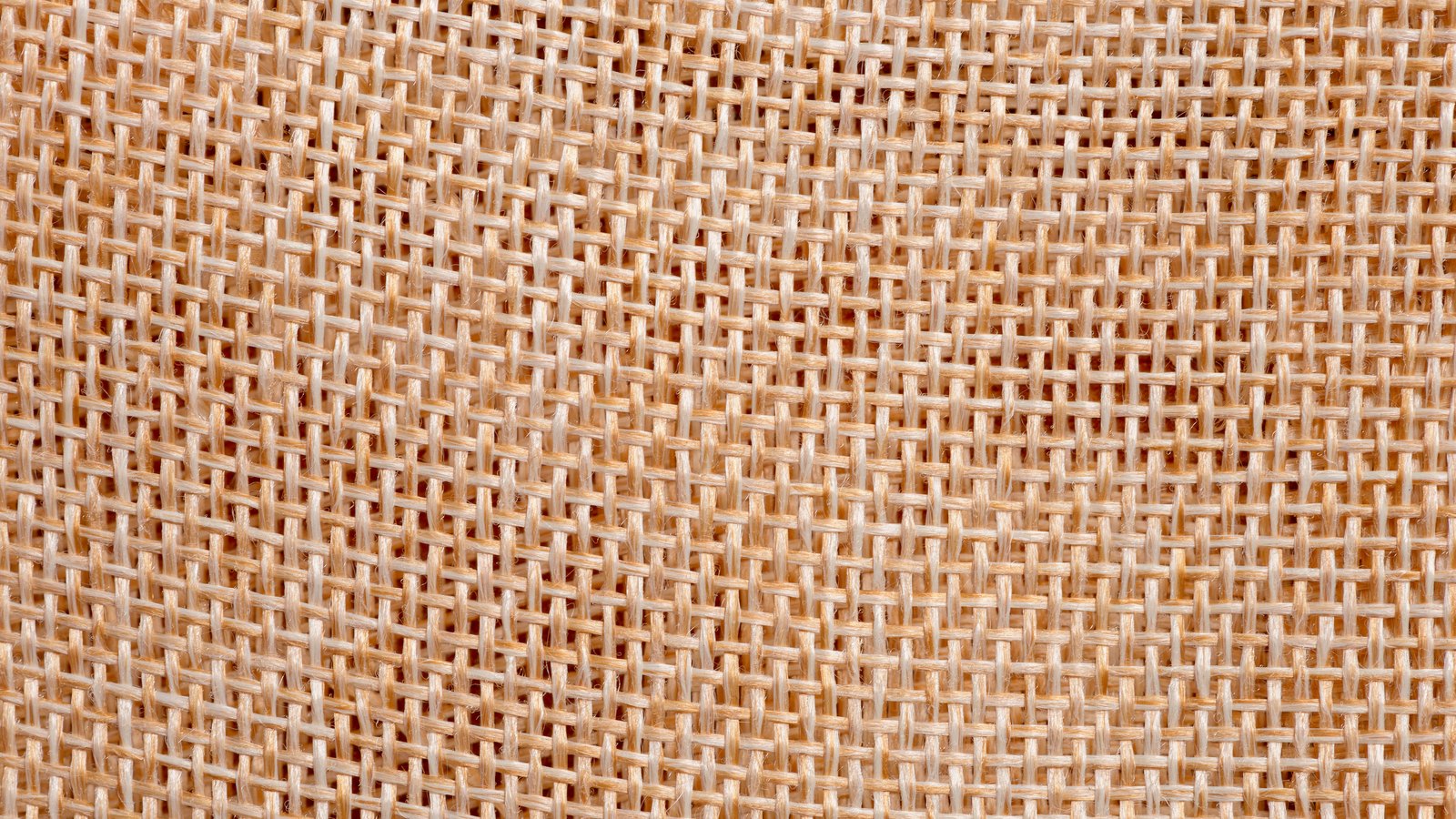 A close view of woven jute fabric, the coarse warp and weft crossing in a regular grid.