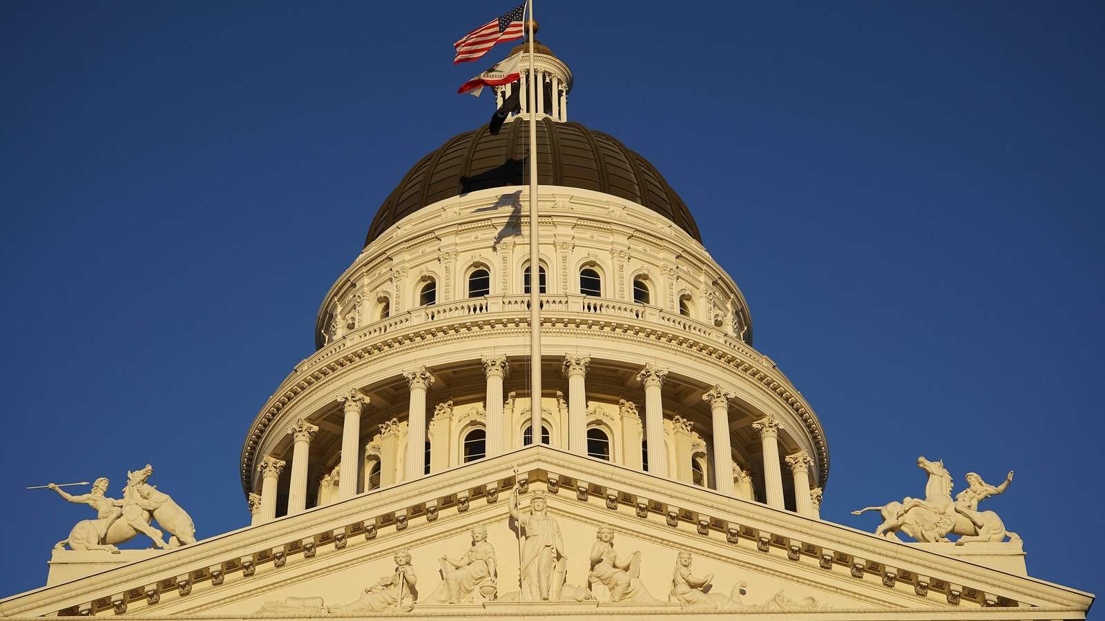 The California State Capitol dome and pediment beneath a clear blue sky.