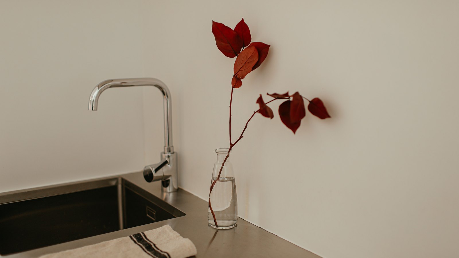 A chrome kitchen faucet stands beside a clear glass vessel, not a photograph of this event.
