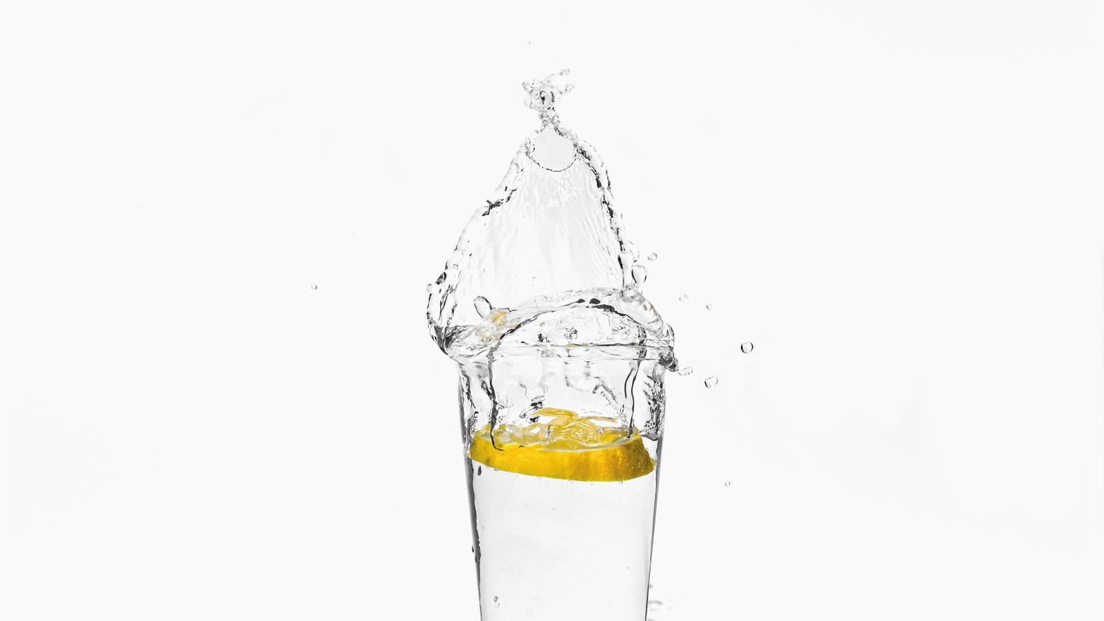 Water splashes around a lemon slice in a clear drinking glass, not a photograph of this event.