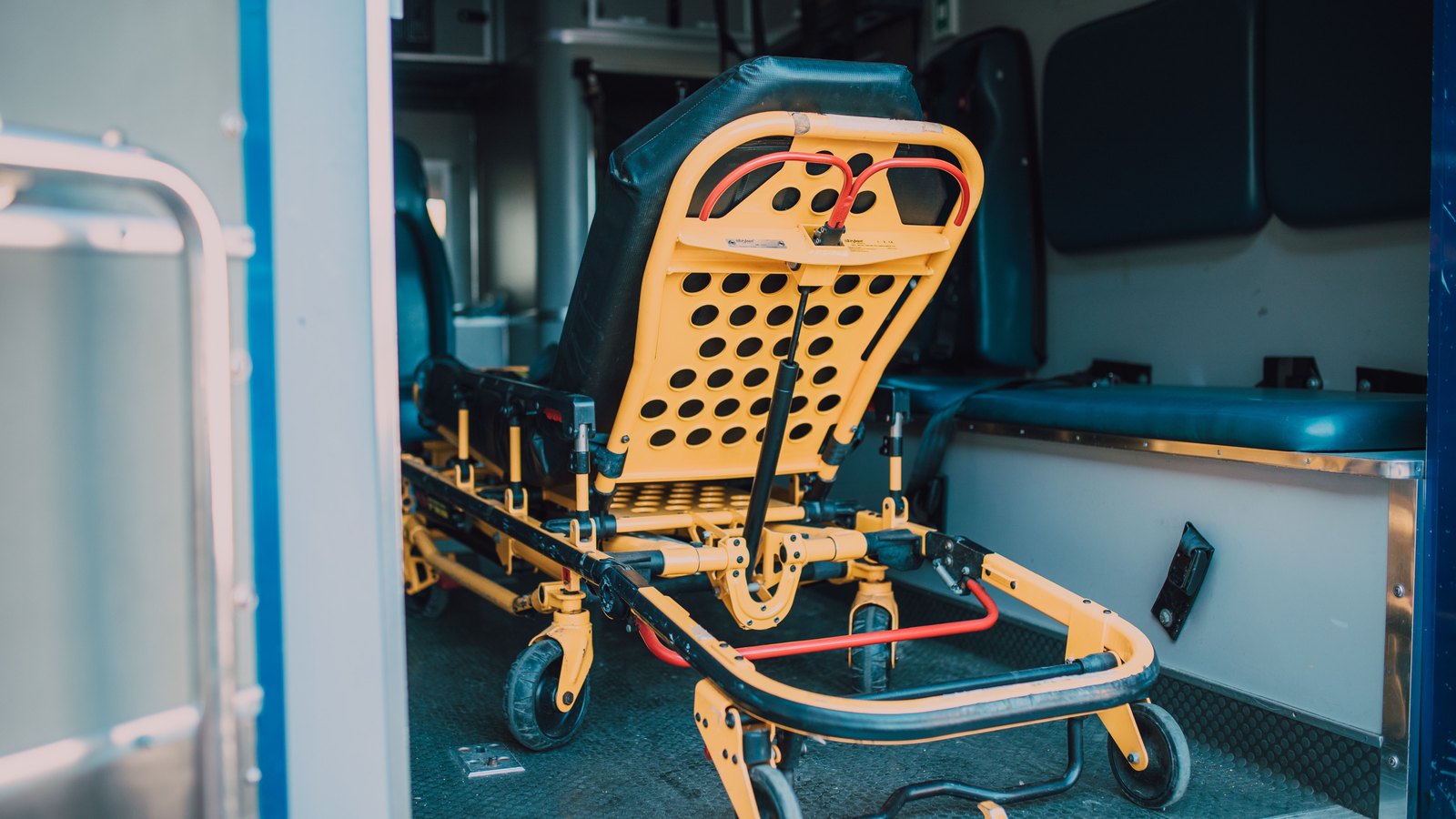 An empty ambulance interior with a yellow emergency stretcher, not a photograph of this event.