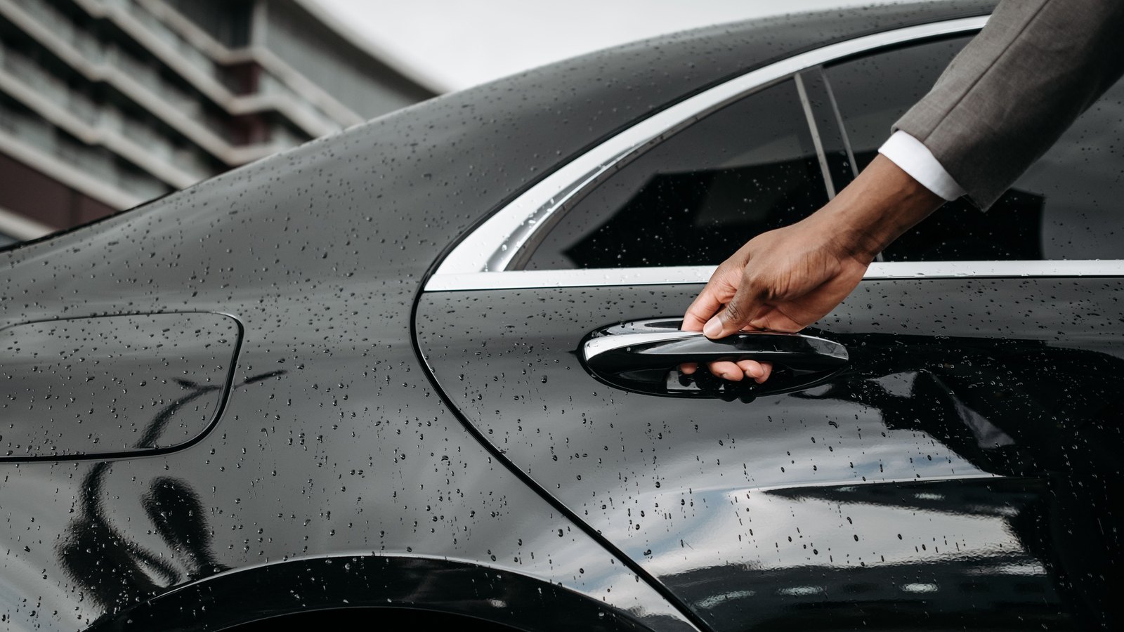 An anonymous hand opens a black car door in the rain, not a photograph of these incidents.