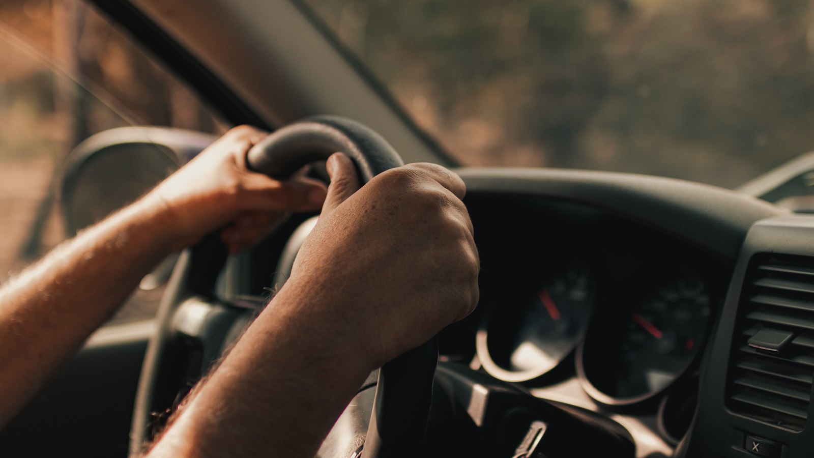 Hands hold an unbranded steering wheel inside a car, not a photograph of this operation.