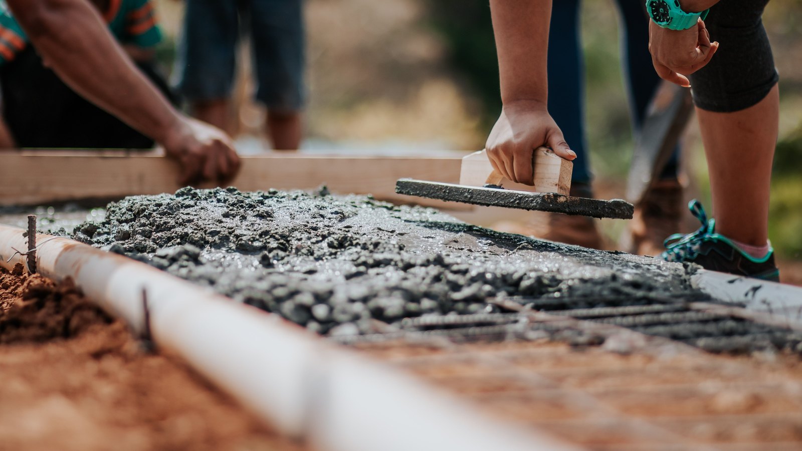 Workers leveling fresh concrete in a ground form, a generic illustration of stabilization work and not a photograph of this repair.