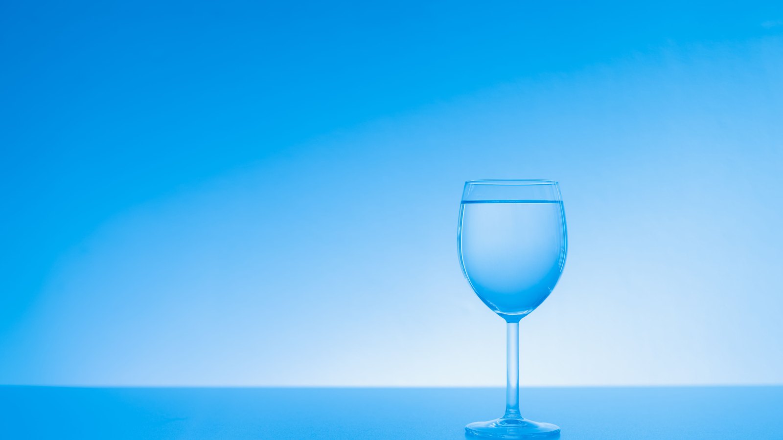 A stemmed glass of clear water stands against a blue background, not a photograph of this advisory.