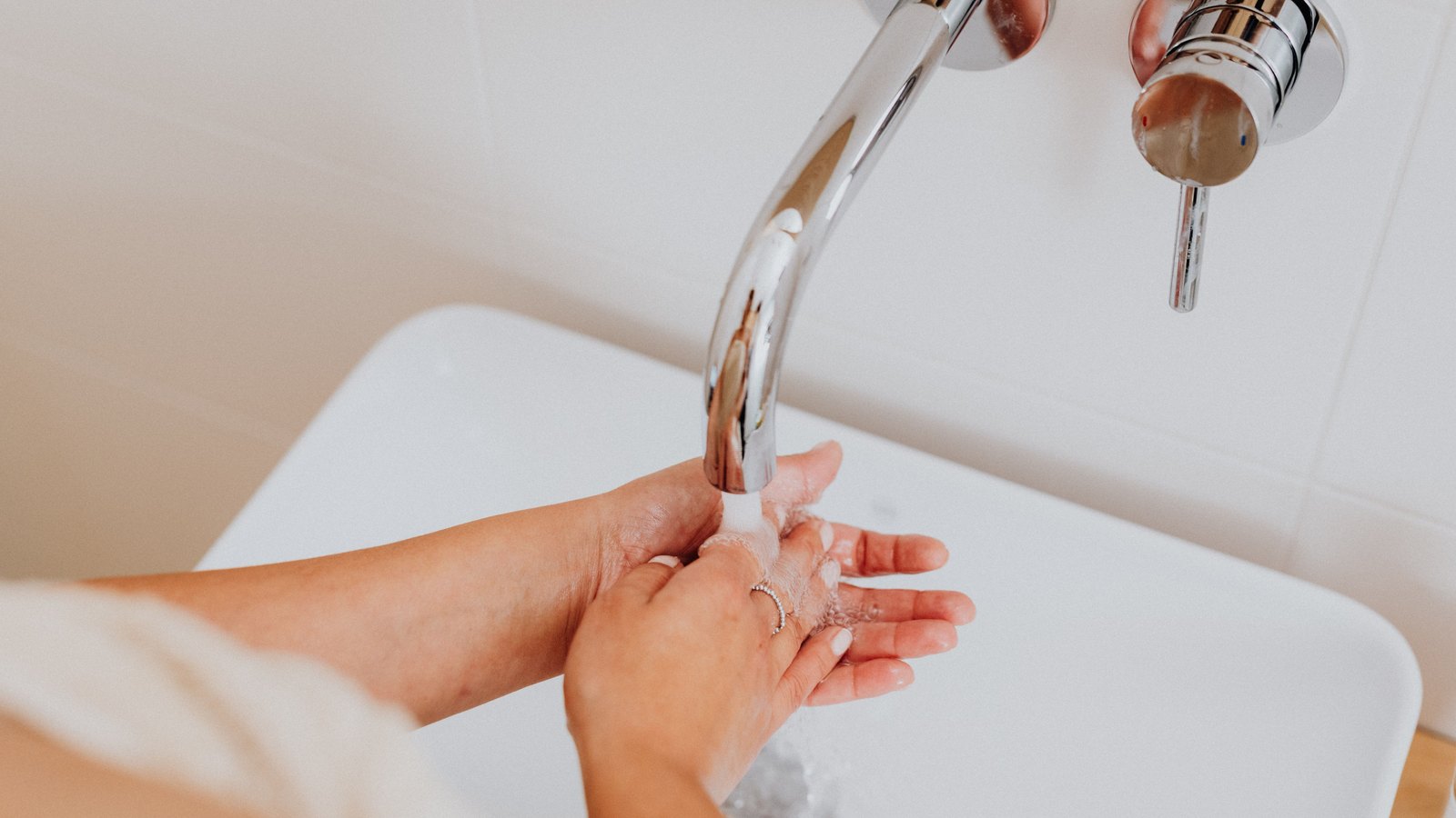 Hands are washed beneath a running chrome faucet, not a photograph of this advisory.