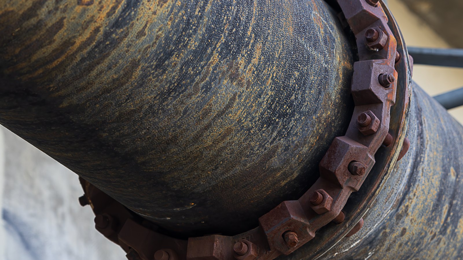 A close crop of a large iron water pipe at a rusted bolted flange joint, used as an illustration. It is not a photograph of the Cape Coral break.