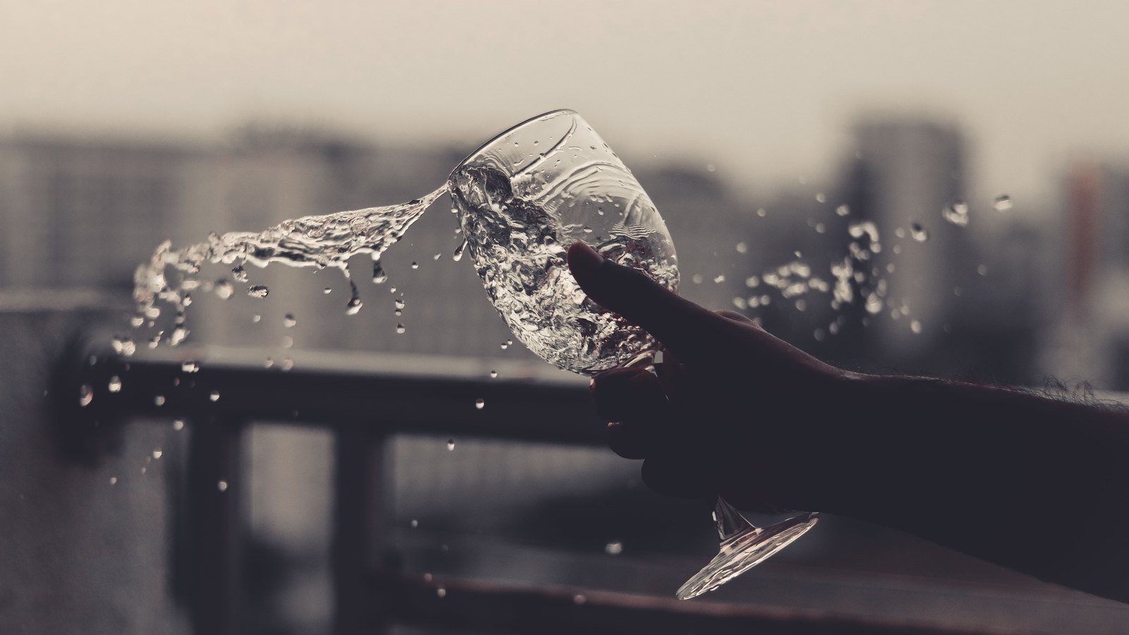 Water splashes from a stemmed glass held by an unidentifiable hand, not a photograph of this event.