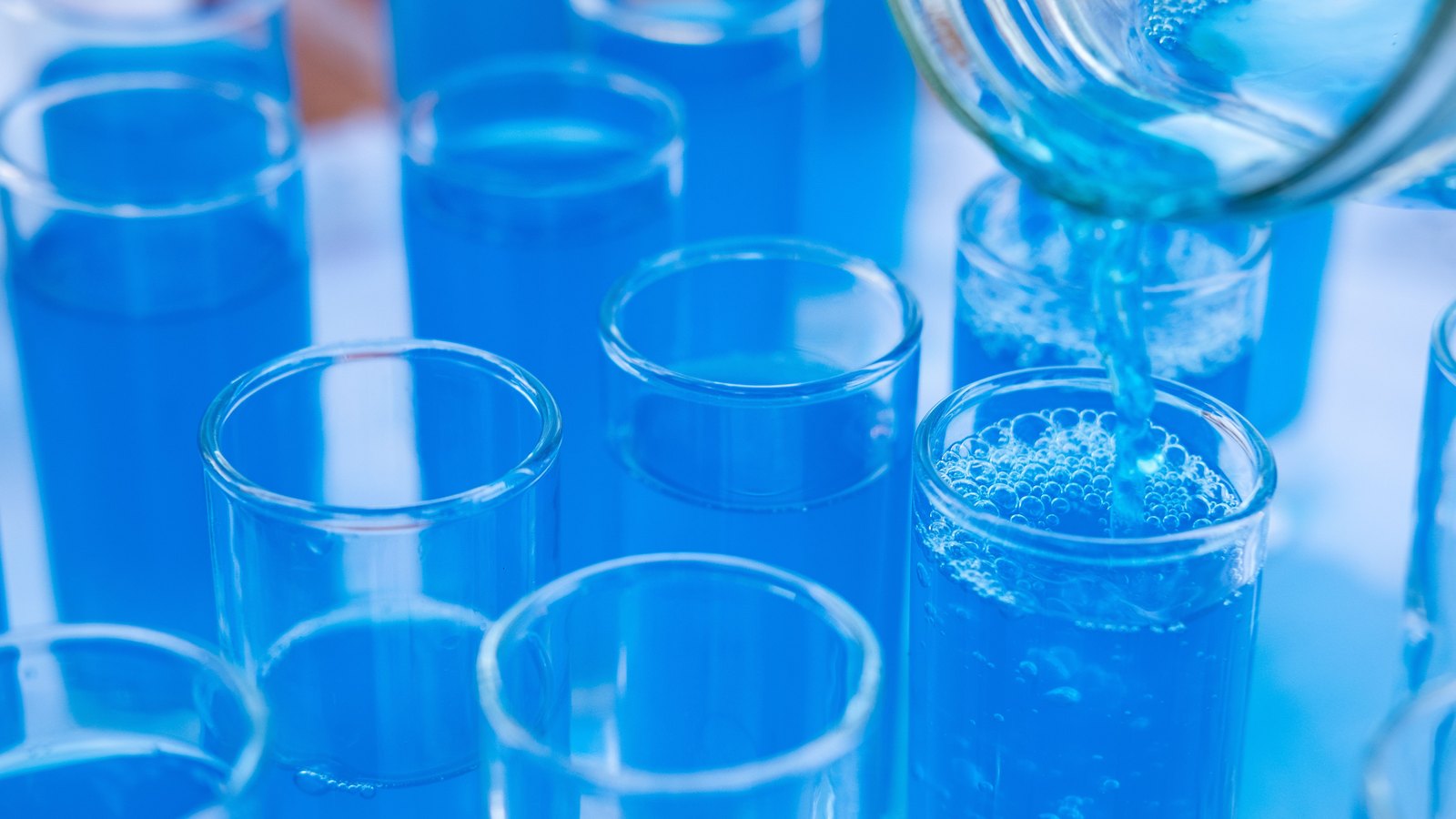 Laboratory test tubes receiving blue liquid during an experiment