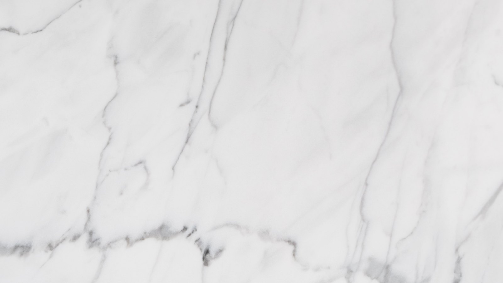 A close photograph of white marble filling the whole frame, fine grey veins branching across a pale polished surface. No text, brand mark, person, edge or object outline is in view.