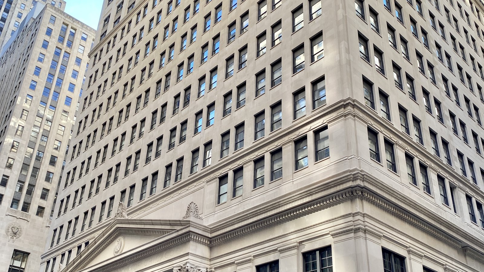 The Federal Reserve Bank of Chicago building seen from street level beneath a blue sky.