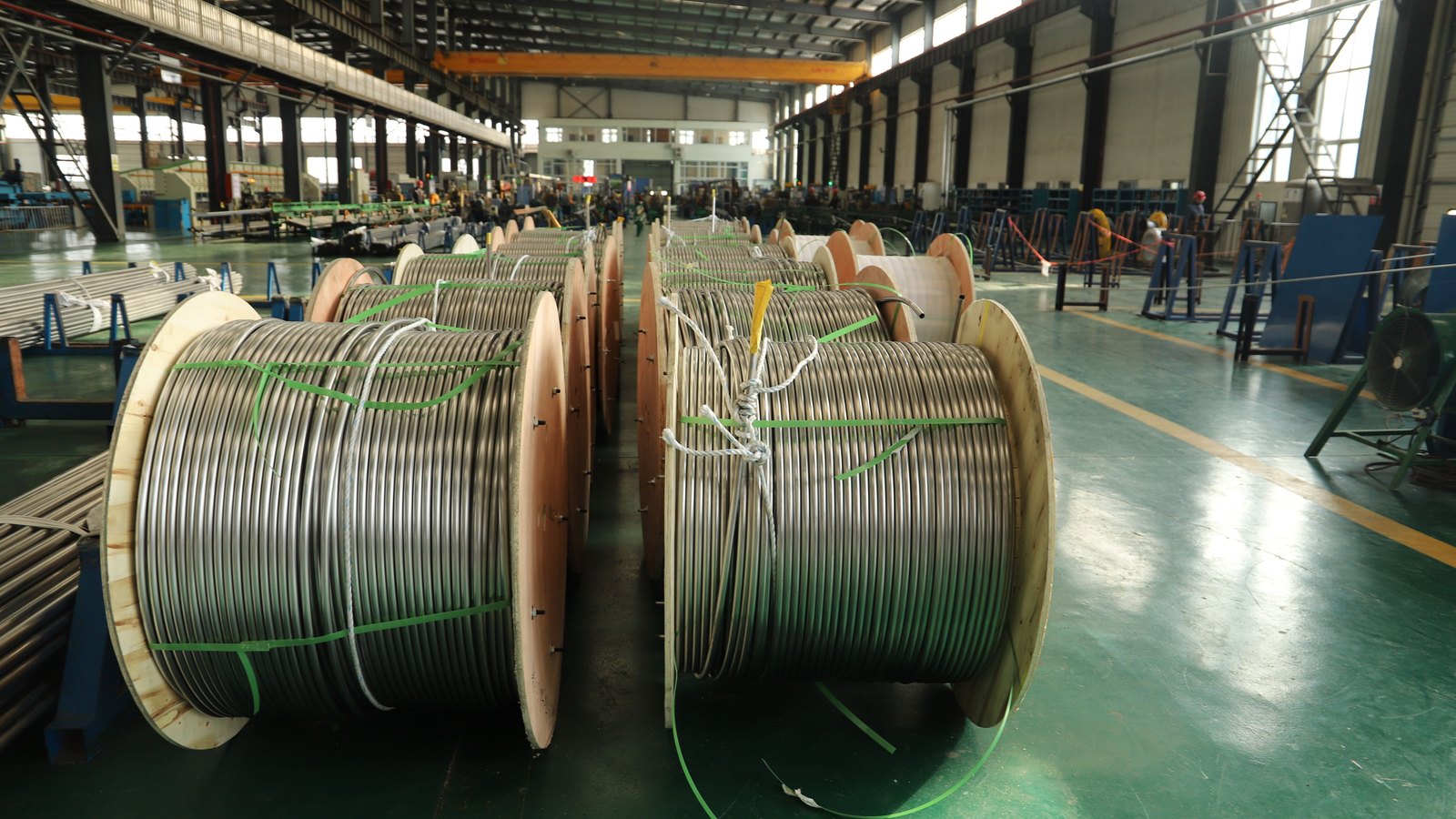 Large reels of metal cable line a manufacturing floor