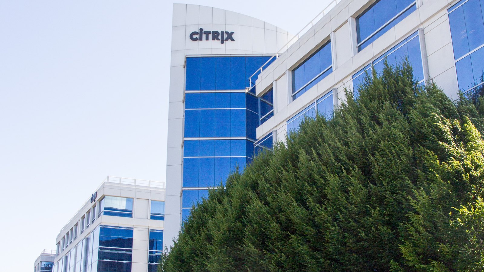 Citrix logo signs in front of a blue-glass office building.