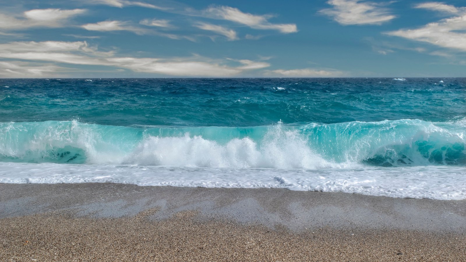 A breaking wave reaches an empty sandy beach in a generic stock photograph, not a photograph of current Lee County conditions.