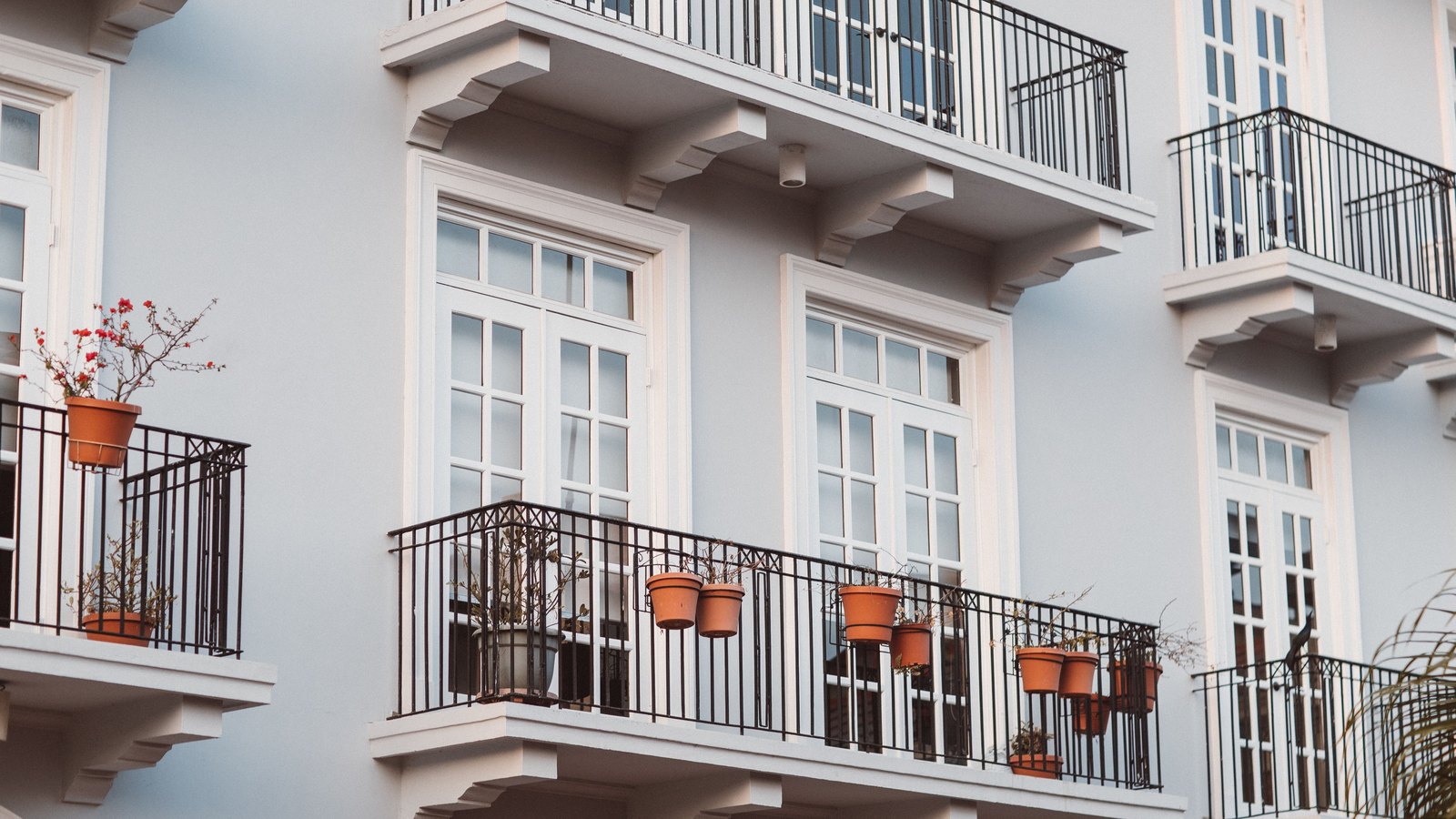 White residential balconies with black railings and potted plants, not a photograph of this event.
