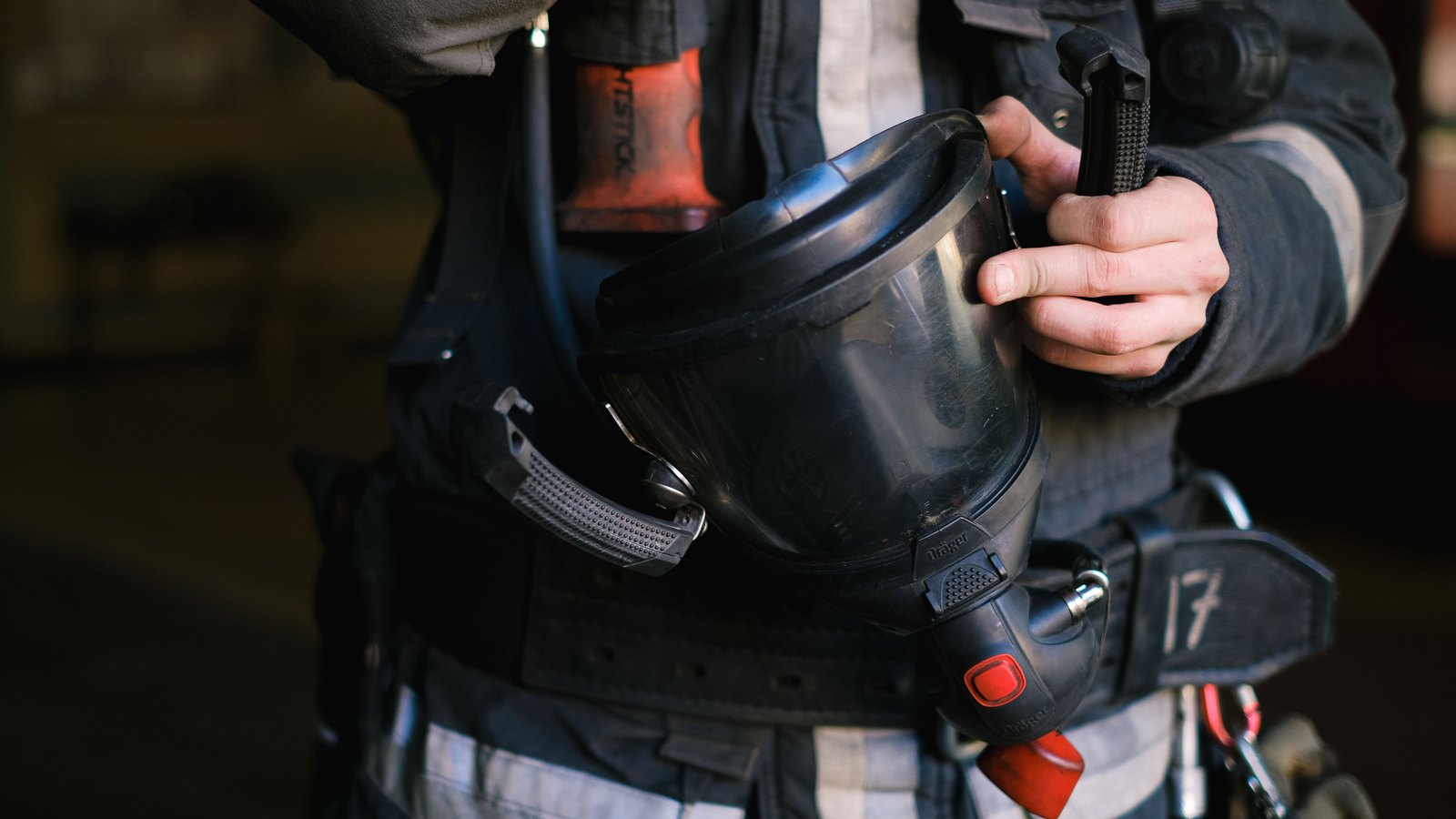 A firefighter holds protective breathing equipment, a stock image not a photograph of this event.