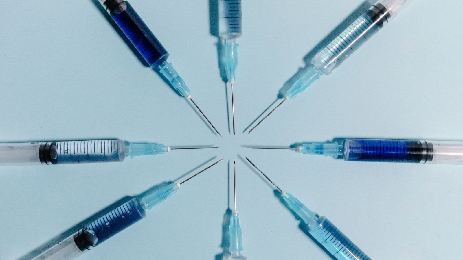 Unbranded syringes arranged on a blue surface. Stock photo, not a photograph connected to a Collier County case.