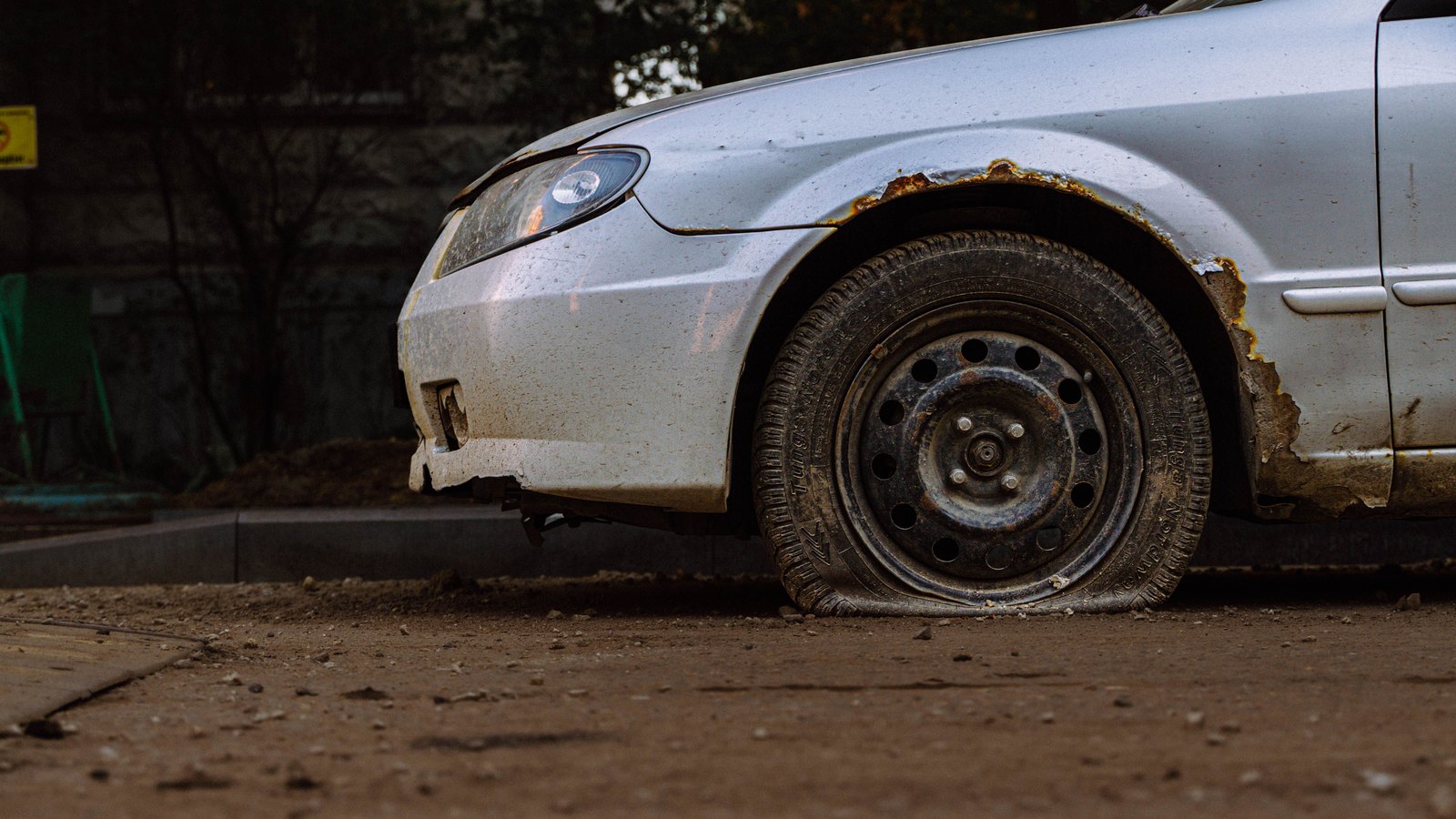 A disabled car with a flat front tire at the roadside, not a photograph of this event.