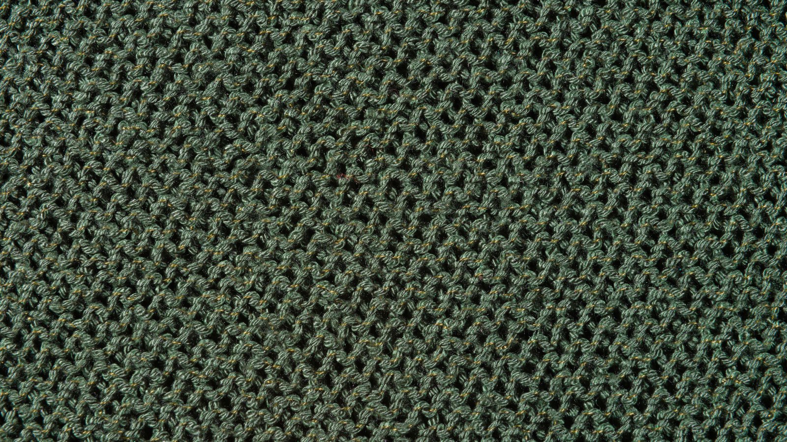 A dark green knitted cloth filling the whole frame, its even rows of looped stitches leaving small open gaps between them, with no edge, seam, label or lettering anywhere in the picture.