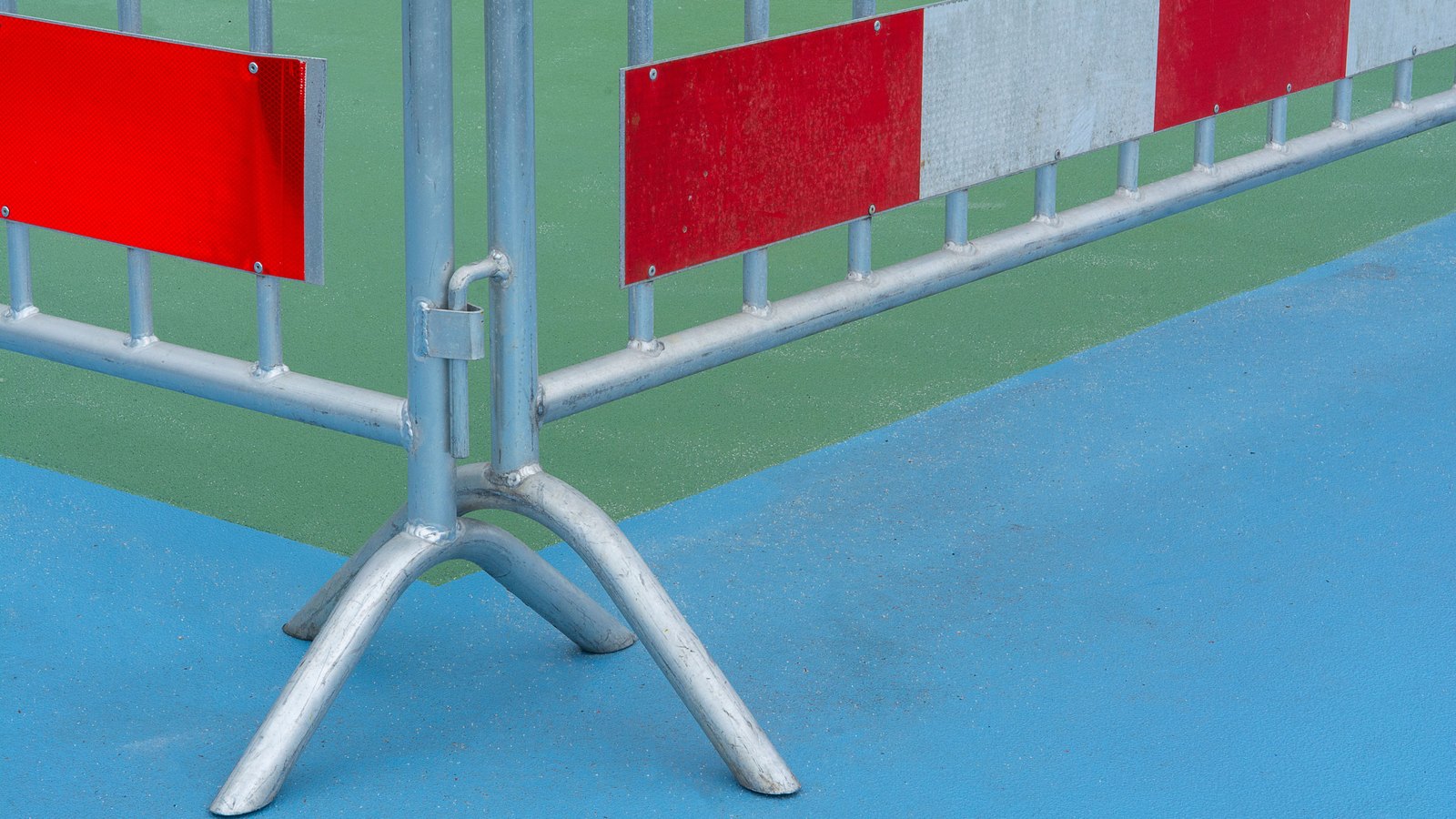 Metal safety barriers with red and white panels on painted pavement, not a photograph of this event.