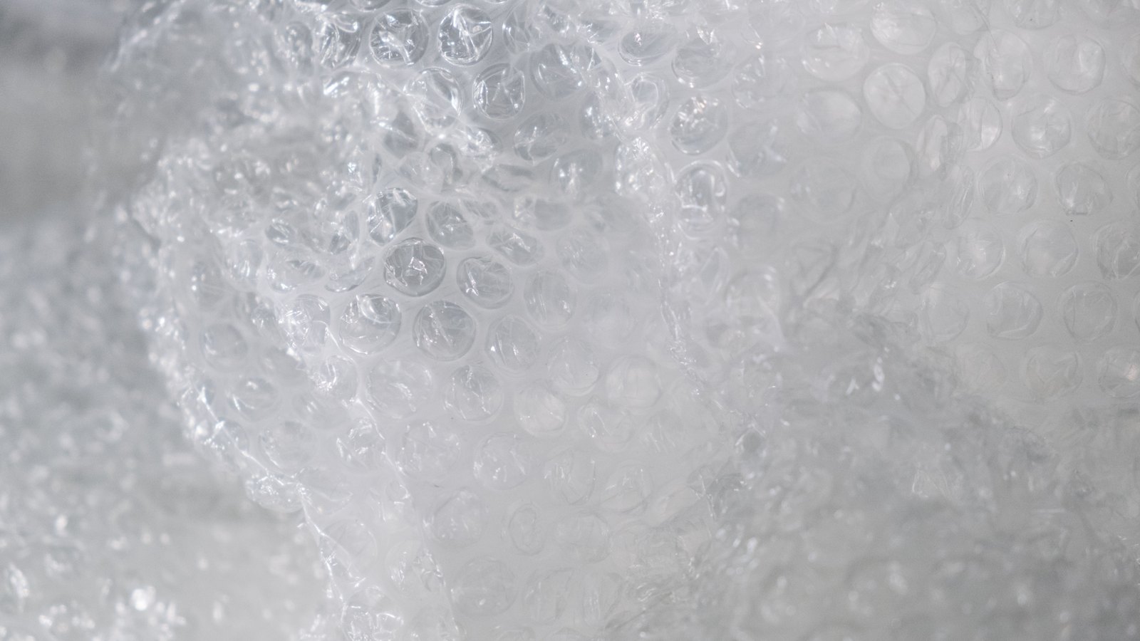 A close photograph of clear plastic bubble wrap, folded so that the rows of air pockets run away from the camera and soften into blur towards the right of the frame. No object, person, lettering or brand mark is visible.