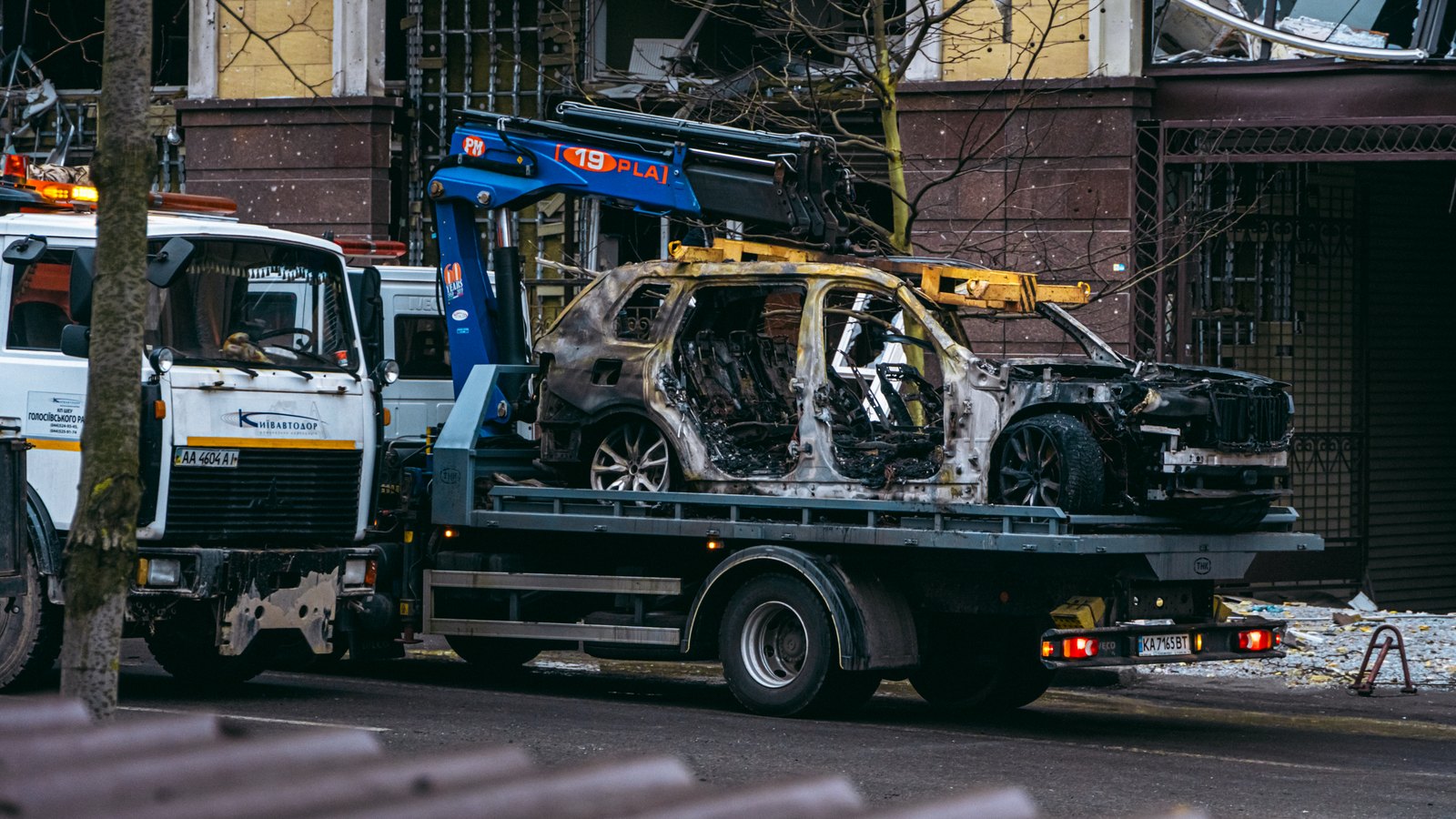 A photograph illustrating tow truck loading damaged car highway emergency lights.