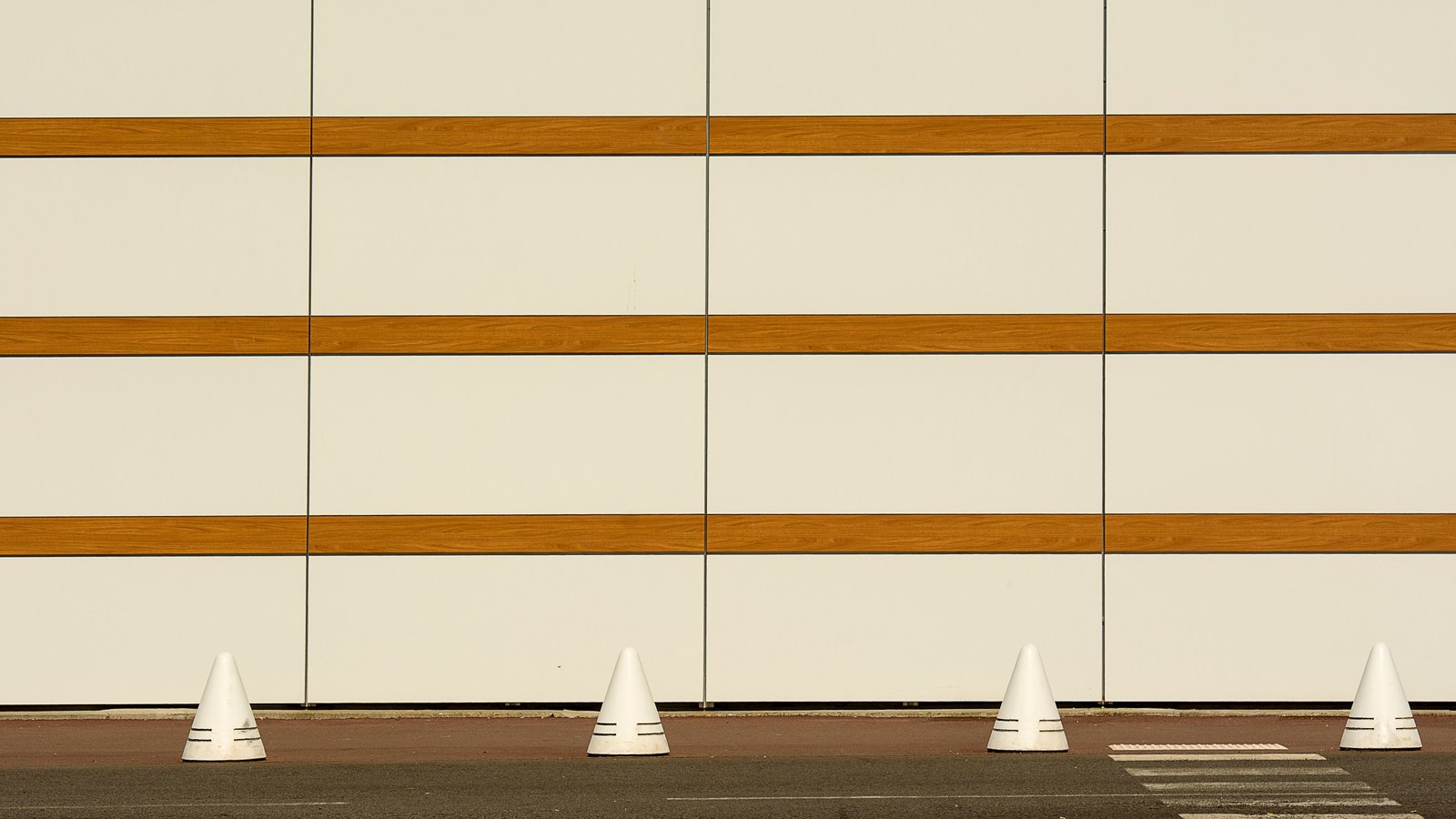 Four pale traffic cones stand beside a striped wall, not a photograph of this event.