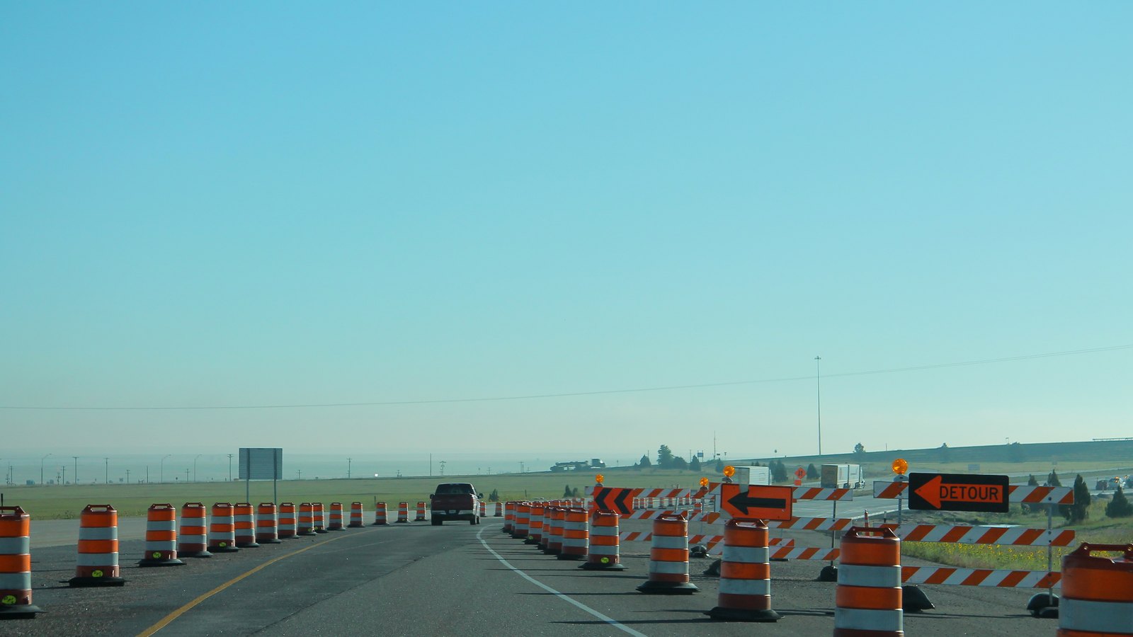Orange construction barrels and generic detour arrows channel traffic through a highway work zone on flat ground. No person, place name, company logo or licence plate is identifiable. It is an illustrative stock photograph, not a photograph of the Daniels Parkway closure.