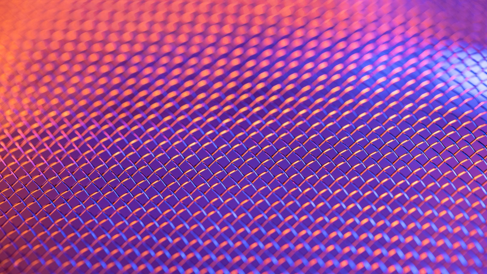 A photograph illustrating tight grid of small square apertures in a fine pale metal mesh screen macro.