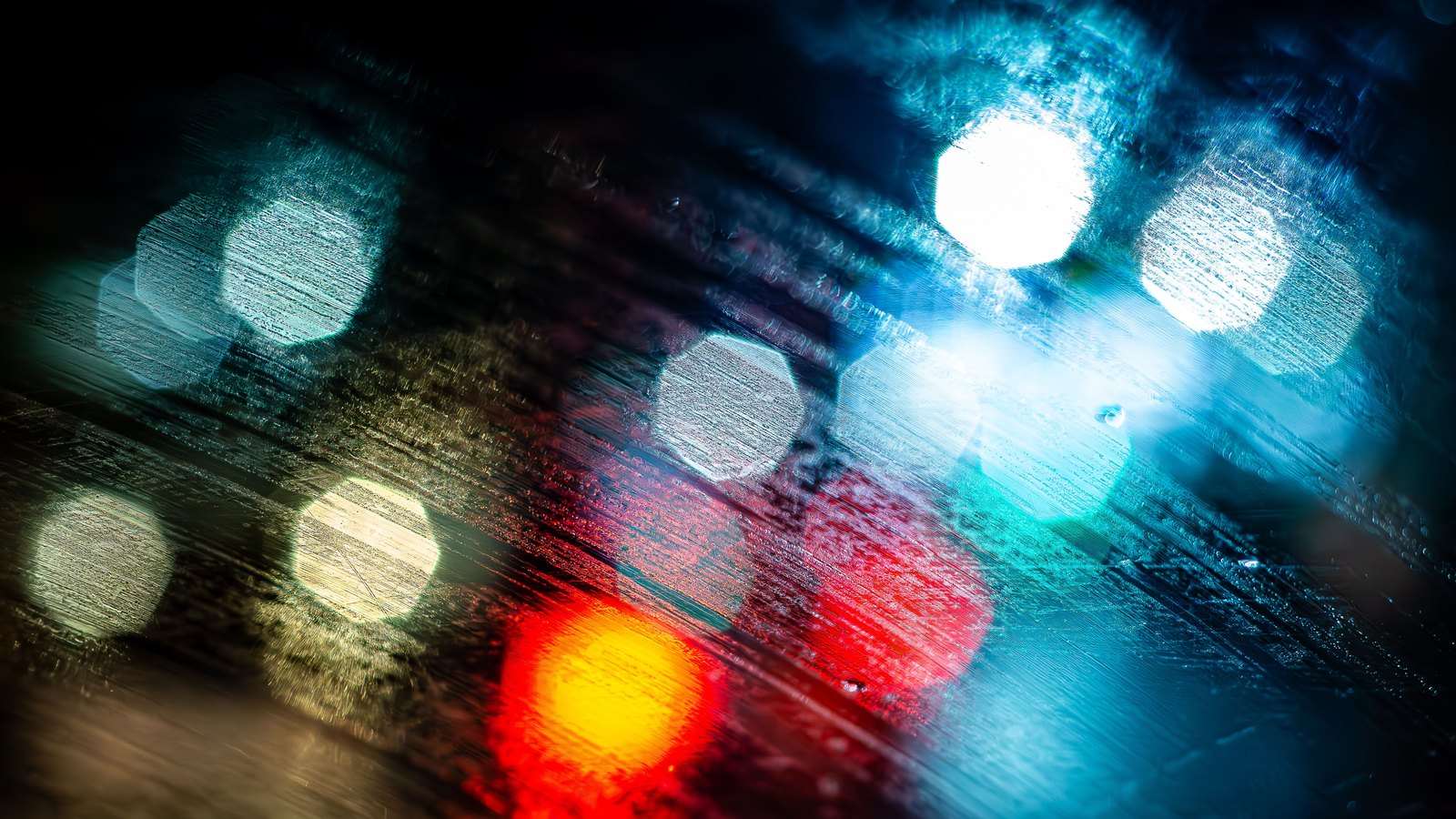 Red and blue lights blur behind rain streaked glass at night, not a photograph of this incident.