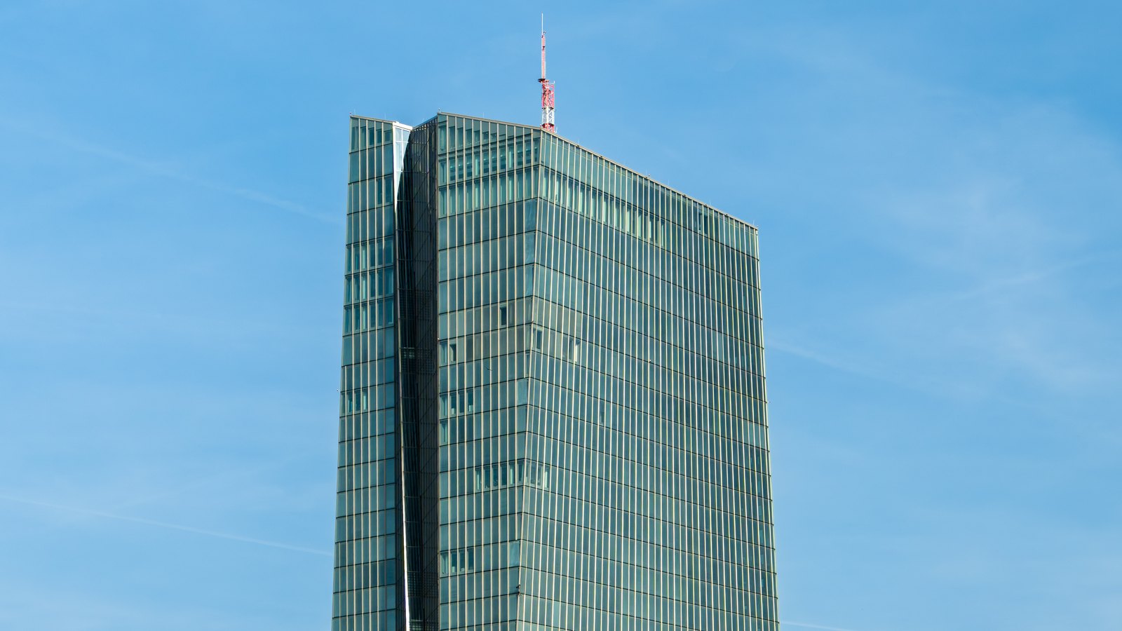 The upper glass towers of the European Central Bank headquarters against a blue sky.