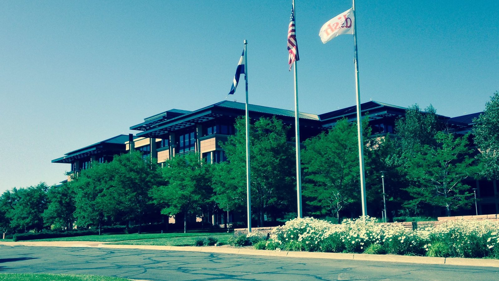 The DISH Network headquarters building in Englewood, Colorado, behind company, United States and state flags.