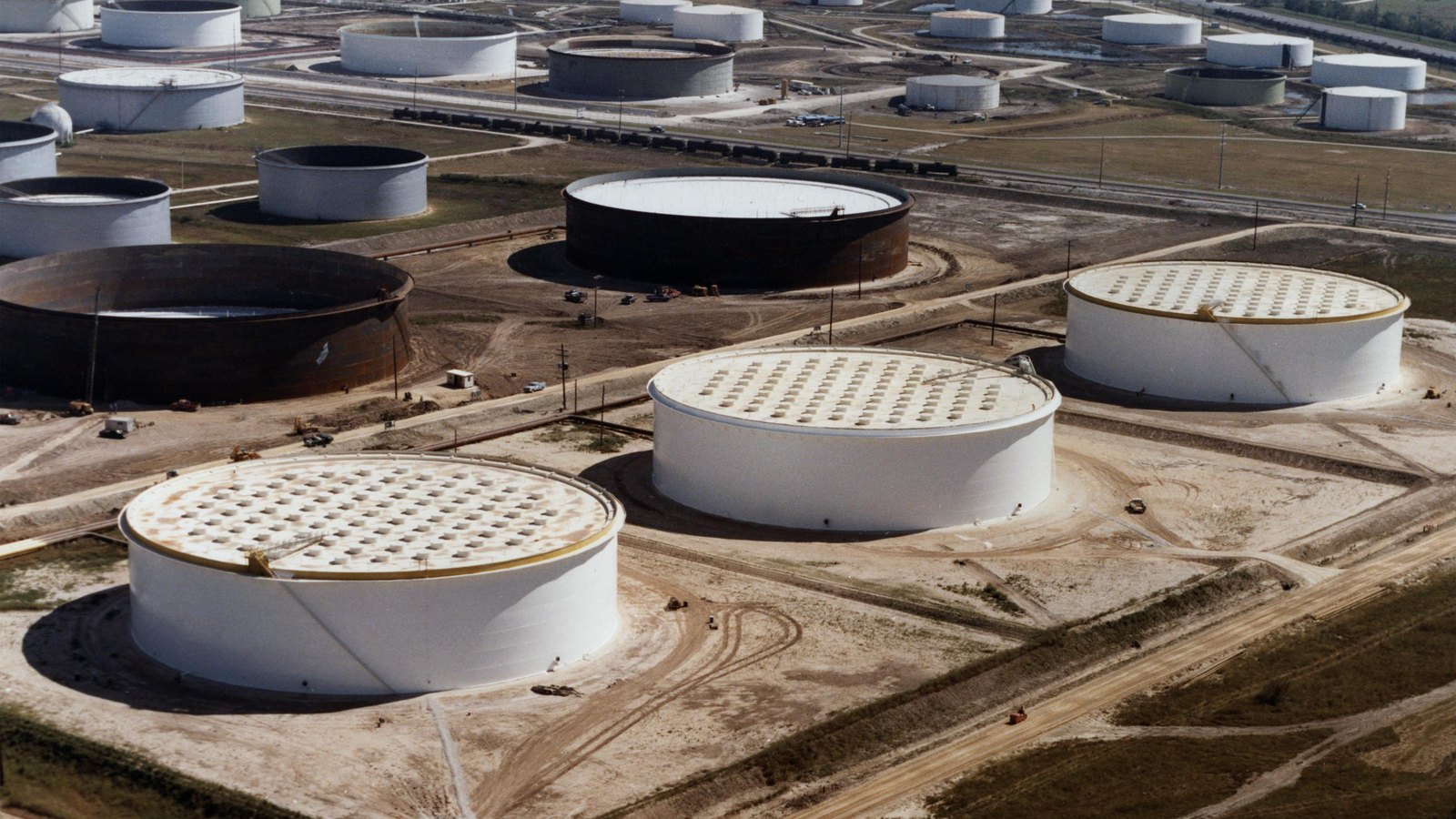 Large petroleum storage tanks stand across an industrial site.